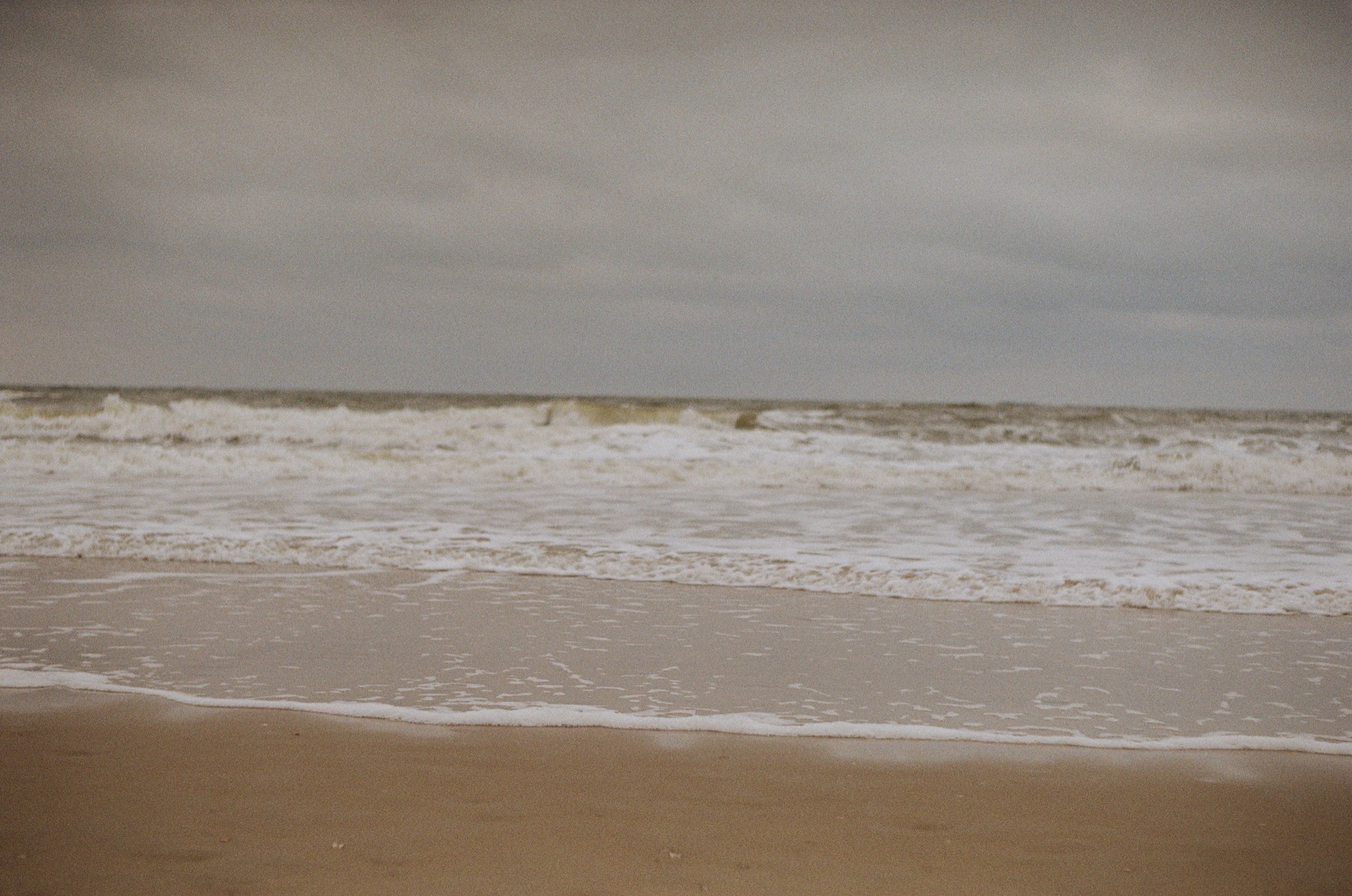 Waves rolling onto a beach beneath a grey sky